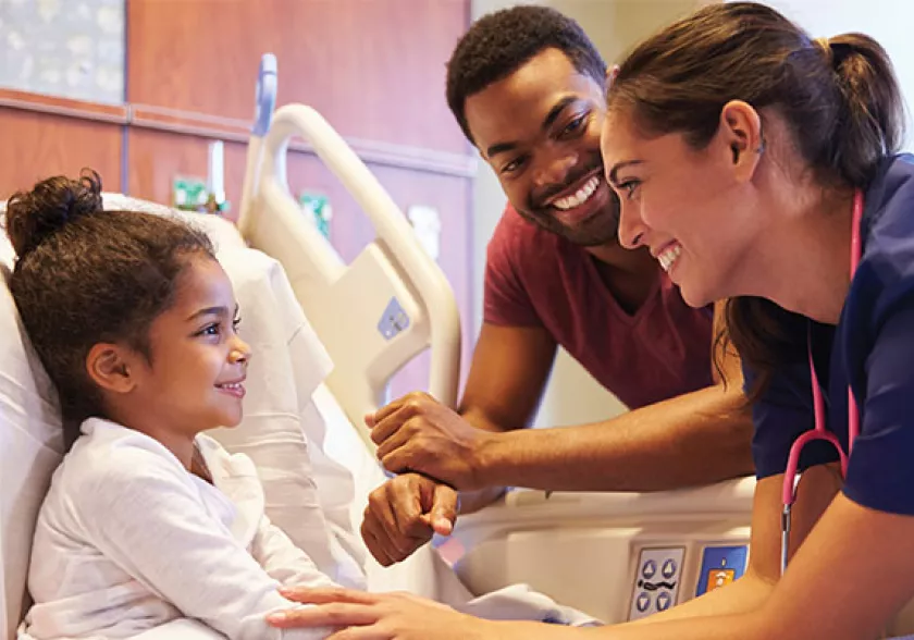 Nurse looking after child with her parent looking on