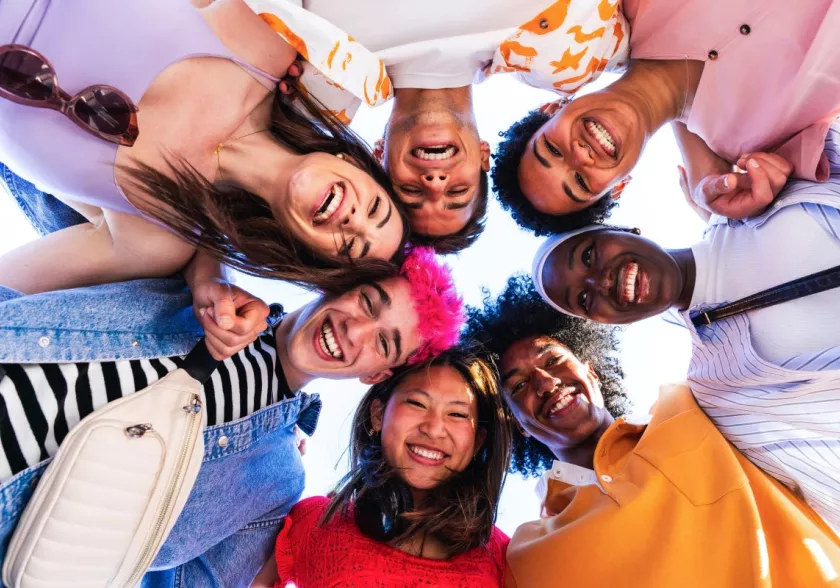 Group of young people in a ring looking down and smiling