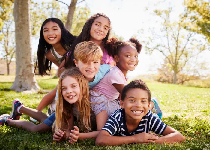 Group of happy children piled up in grassy park