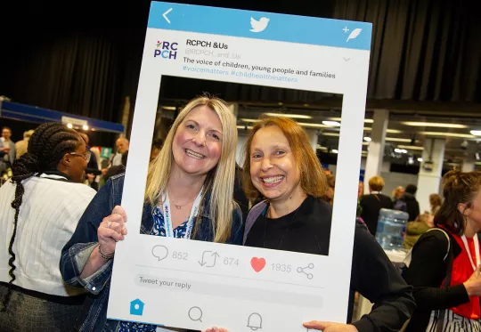 two women smiling behind social photo booth