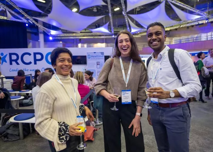 Three people in a busy conference hall, laughing