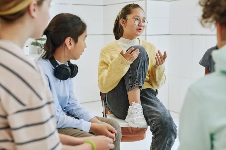 Teenage girls sit in a group, talking