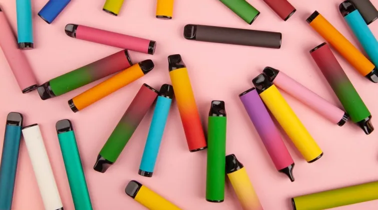 Many vapes scattered on a pink background