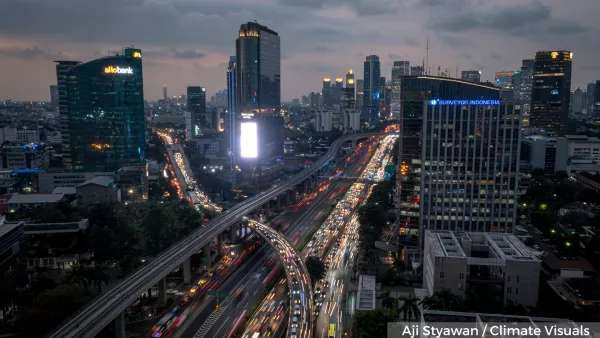Image depicts a city skyline at night with a busy road surrounded by tall buildings