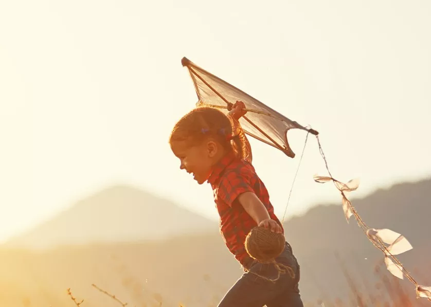 A child running outside holding a kite