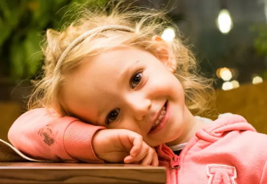 Young girl smiling with head resting on her arm