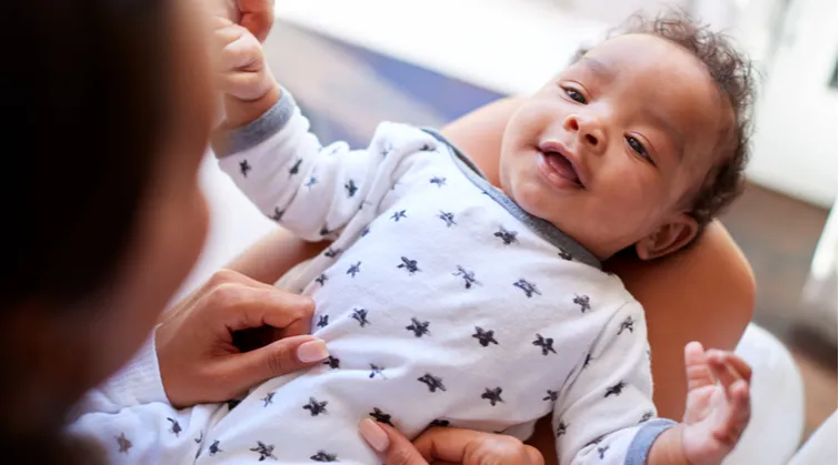 Baby is smiling while laying down on mum's lap