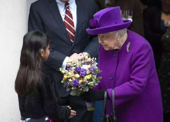Queen receives flower bouquet from a child 