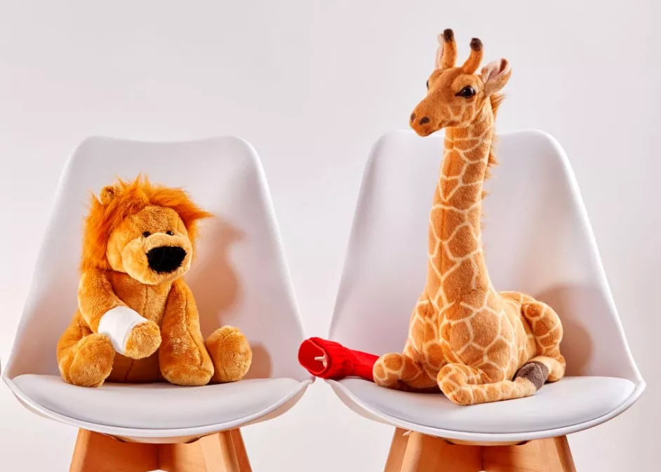 Stuffed animals with bandages and a hot water bottle on chairs