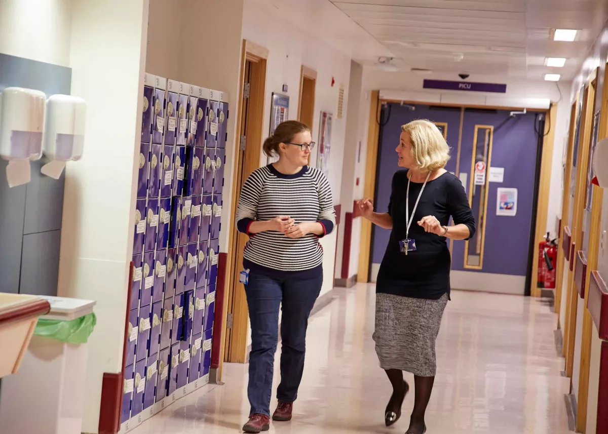Two people talking while walking down hospital corridor 