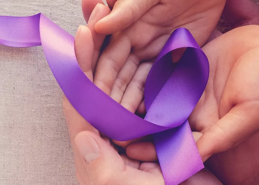 Hands holding purple ribbon