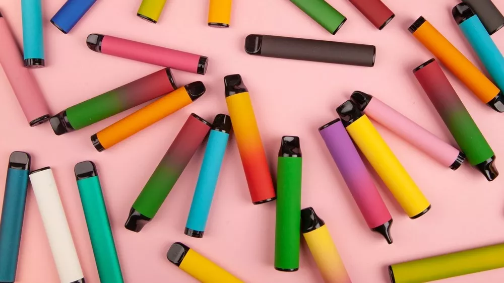 Many vapes scattered on a pink background
