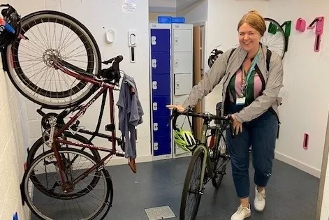 Woman with bicycle next to stored bicycles and lockeres