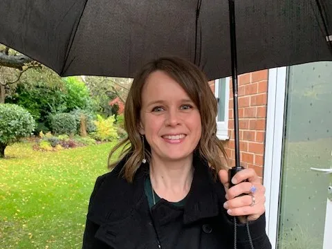 Dr Anne Pinches Anne Pinches, smiling, under large umbrella