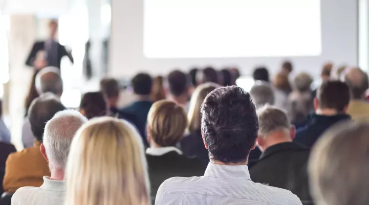 Large group of people seated, from back of an auditorium