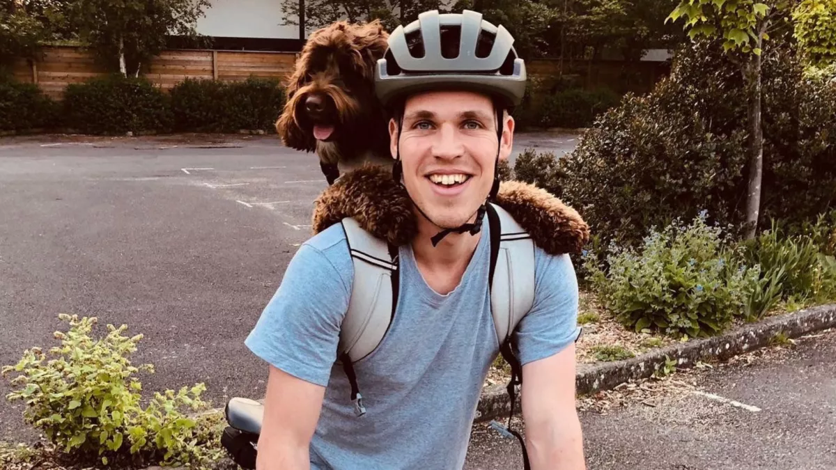 Harry Apperley with his dog in a backpack and on a bike