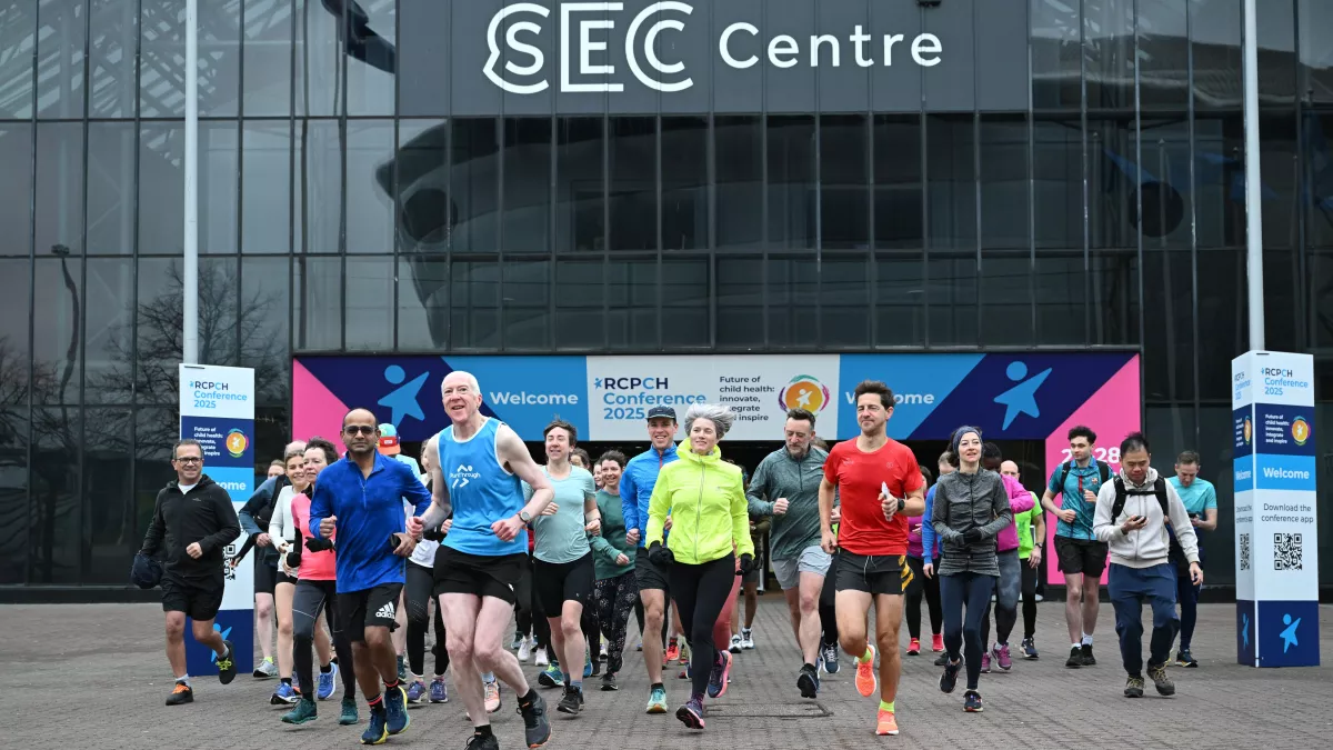 Large group of people running, with SEC Centre in background, with RCPCH Conference signs