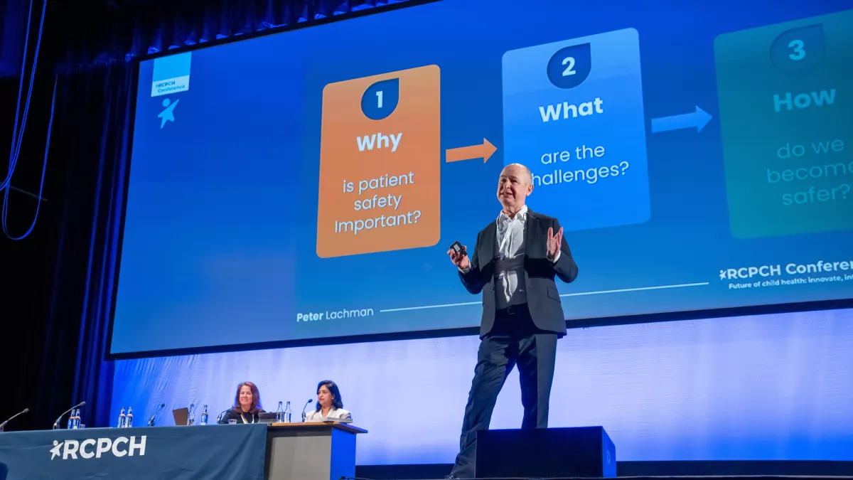 Peter Lachman speaking on stage, with slide reading "Why is patient safety important? What are the challenges? How do we become safer?!