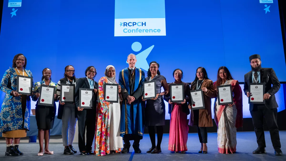 Visiting Fellows present their certificates on stage, with RCPCH President