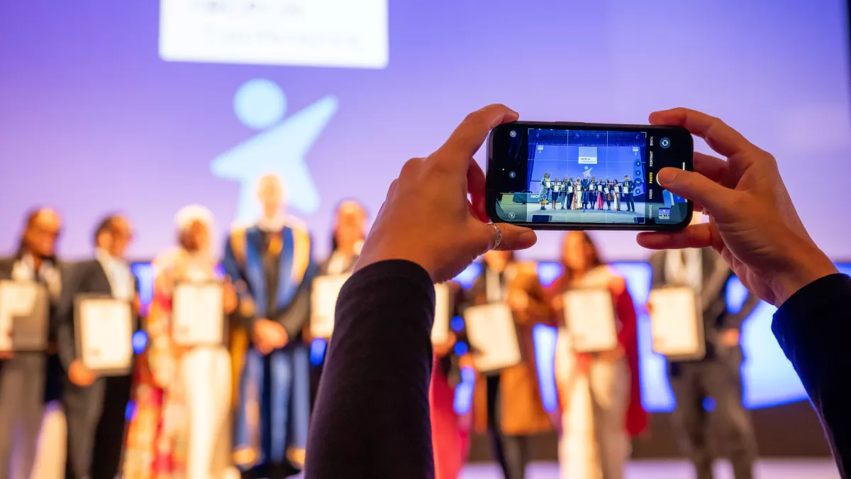 Someone taking a photo on mobile phone of people on stage