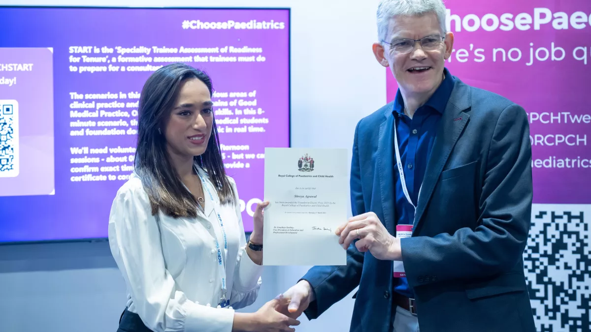 Two people, one presenting a certificate to another, with RCPCH #ChoosePaediatrics banner and slide in the background 