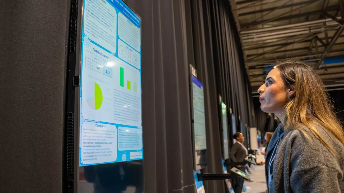 Woman looking at an ePoster on a digital screen, with more screens in the background 