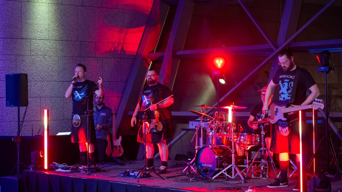Musical band on stage, wearing kilts, with guitars and drums