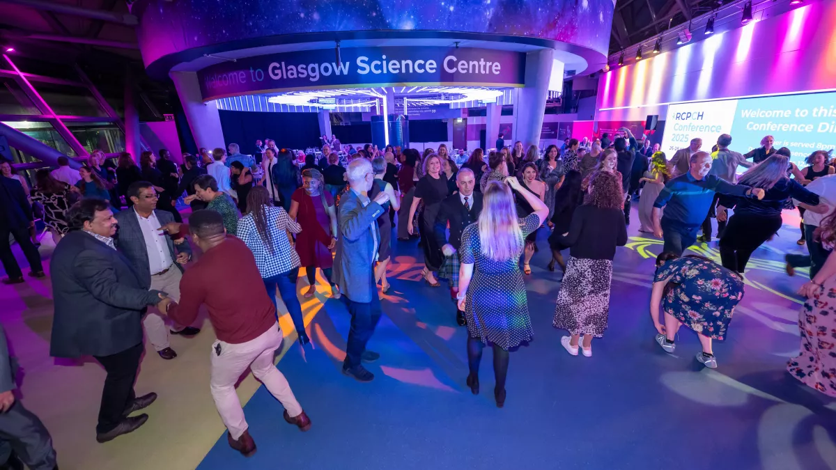 Lots of people dancing the ceilidh, with Glasgow Science Centre sign