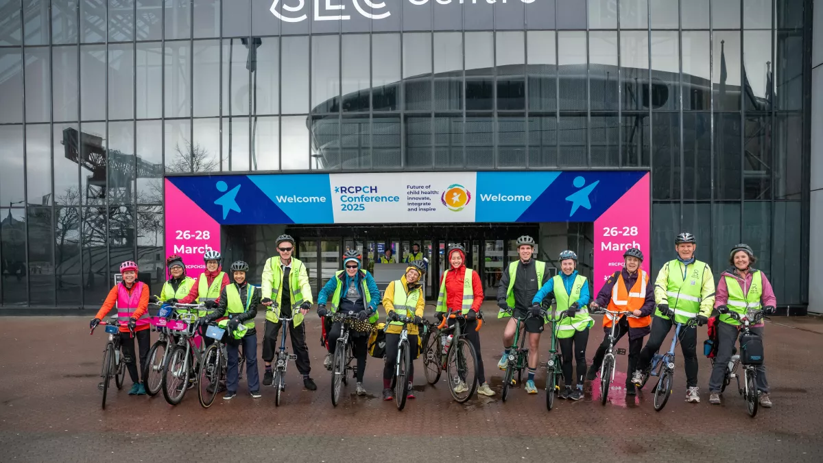 Group of cyclists outside building with SEC Glasgow and RCPCH Conference signage