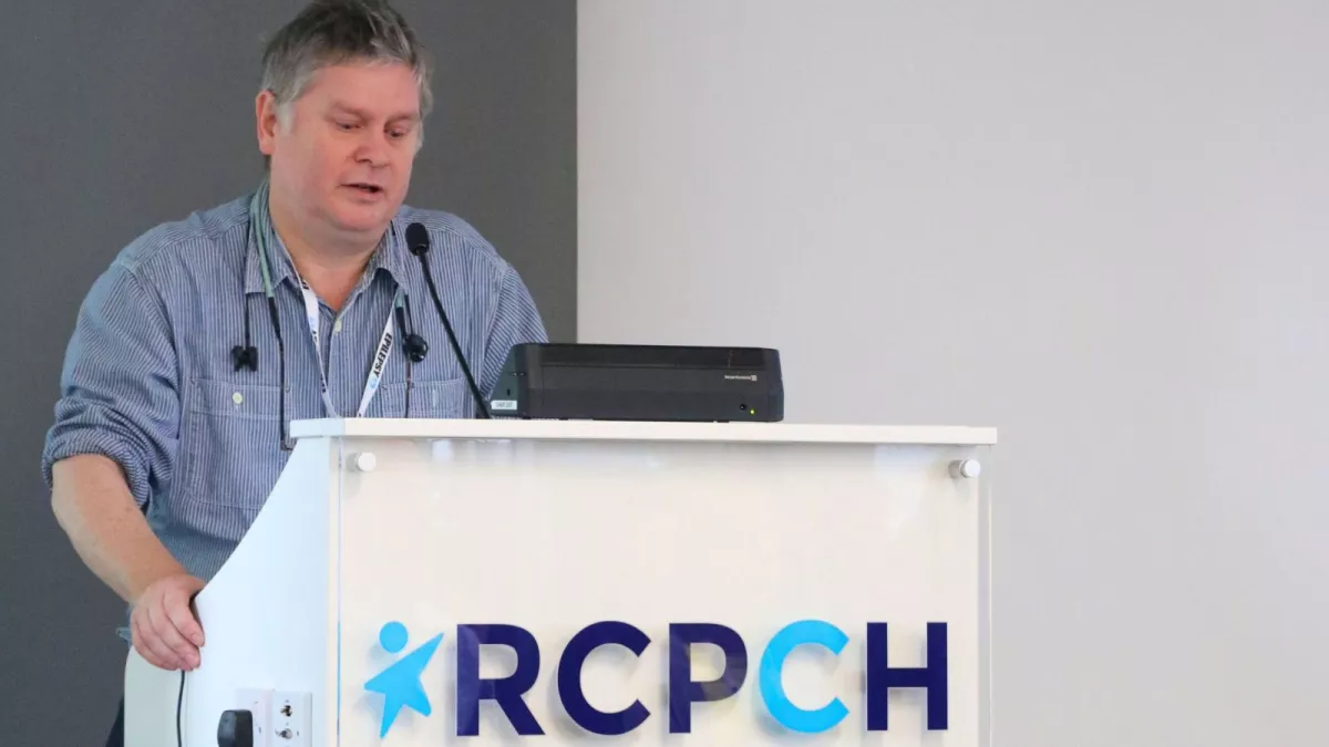 Man presenting from a podium that reads RCPCH