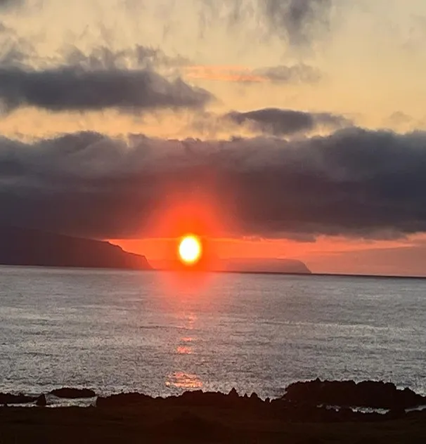 Photo of sunset over a quiet sea, with clouds