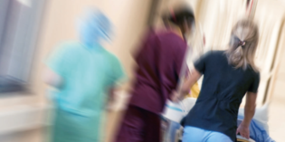 Patient trolley and health professionals in hospital corridor, blurred