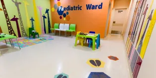 Inside of a children's hospital waiting area, with Paediatric Ward and animal stickers on colourful walls, plus toys and games